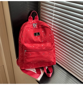 Detail of red canvas backpack with silver star patterns and metallic brand plate