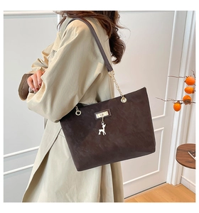 Detail of dark brown matte shoulder bag featuring a deer charm and metal chain strap