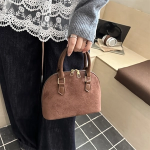 Retro brown suede handbag with embossed heart detail and gold zippers in casual setting