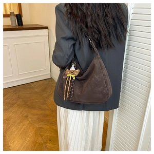 Detailed back view of a vintage dark brown suede handbag styled with a cute bear charm