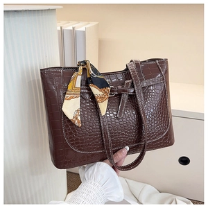 Dettaglio borsa tote marrone scuro con trama a coccodrillo e foulard di seta decorativo