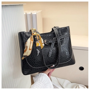 Dettaglio borsa tote in pelle di coccodrillo nera con cuciture a contrasto e foulard