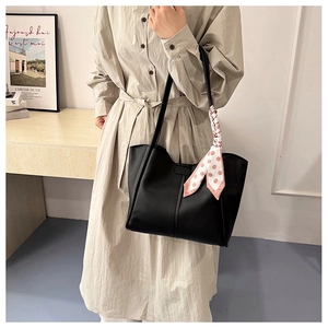 Close-up of black PU leather tote bag with a pink polka dot silk scarf on the handle