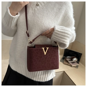 Vue détaillée d'un sac bandoulière rouge foncé imprimé léopard avec une boucle dorée en V