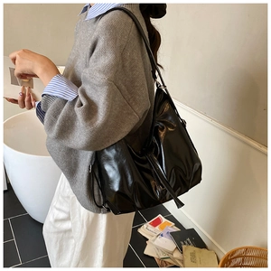 Detalle del bolso hobo grande de charol negro que muestra textura brillante y asa