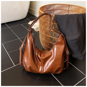 Detalle de un bolso hobo de cuero marrón con cremallera de borla y correa ajustable