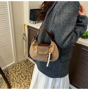 Detail of vintage brown leather half-moon bag with suede trim and wood bead pendant