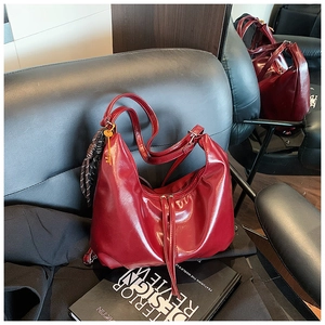 Detalle de bolso hobo brillante rojo oscuro con pañuelo a cuadros y colgante