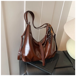 Detalle del bolso tote marrón brillante con correa ajustable y colgante decorativo