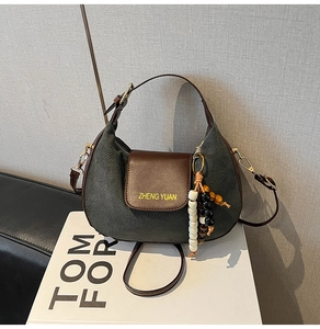 Detail of half-moon shoulder bag with suede texture and wooden bead charm accent