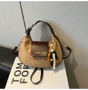 Detail view of khaki suede and brown leather bag with colorful beaded tassel pendant