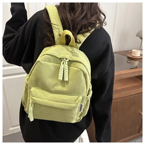 Detail of light green corduroy mini backpack with woven zipper pull and fashion side label