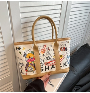 Close-up of graffiti print tote bag with leather handles and street art patterns