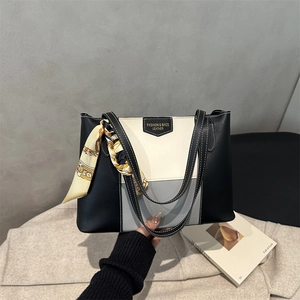 Detail of color-block tote bag with leather logo tag and elegant silk scarf on handle