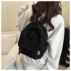 Detail shot of black corduroy mini backpack showing vertical texture and fashion label
