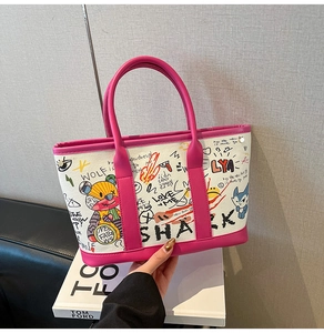 Detail of white canvas tote with graffiti prints and vibrant pink leather handles