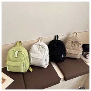 Close-up of ribbed corduroy texture and decorative zipper tags on four mini backpacks