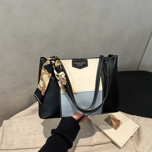 Detail of color-block tote bag featuring black, cream, and blue panels with a silk scarf