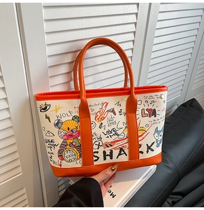 Close-up of stylish tote bag with colorful graffiti art and orange leather trim