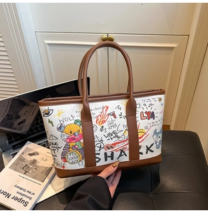Detail of trendy tote bag with street art graffiti and leather trim on a desk
