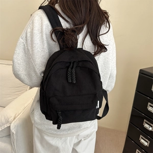 Minimalist black corduroy mini backpack for women featuring woven zipper pulls and fashion tag