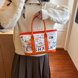 Fashionable graffiti canvas tote bag with orange leather handles for women shown by model