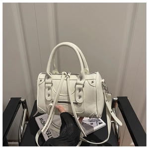 Detail view of cream leather Boston bag with silver studs and long fringe zipper pullers