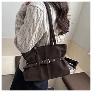 Detail of dark brown tote bag with silver eyelet straps and textured matte finish on a model
