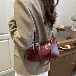 Sac sous le bras minimaliste en cuir verni bordeaux avec breloque nœud argenté
