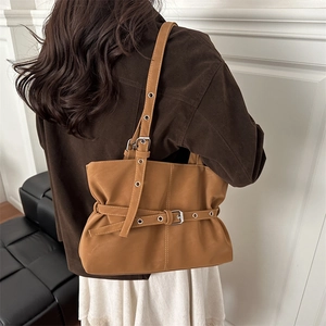 Minimalist brown suede shoulder bag with decorative belt detail shown on a model