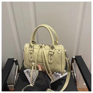 Detail view of yellow vintage boston bag featuring silver studs and leather tassels