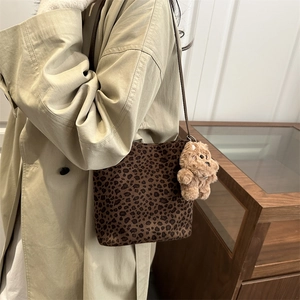 Retro leopard print bucket bag with plush bear charm worn by a model in a trench coat
