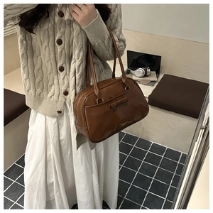 Détail d'un sac cabas en cuir marron foncé avec un nœud décoratif et fines lanières