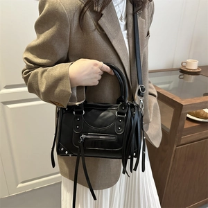Vintage black rivet Boston bag with silver studs and long tassels, shown on a model