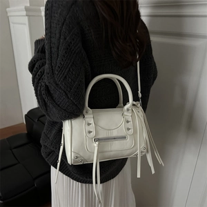 White retro Boston bag with silver rivets and tassels shown on a model for a stylish look