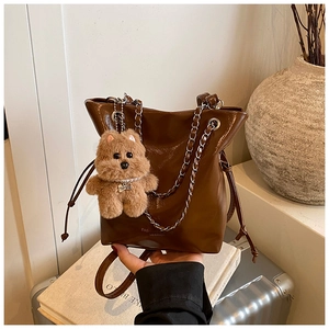 Détail du sac seau en cuir marron foncé avec fermeture à cordon et breloque ours