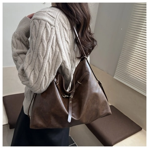 Detailed side view of vintage brown large tote bag worn with a beige sweater