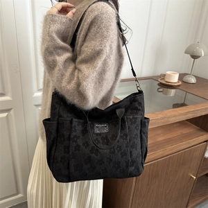 Women's black canvas tote bag with floral pattern and fashion instinct label in soft light