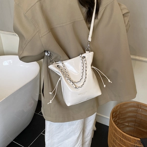 Sac seau en cuir verni blanc avec bretelles en chaîne et détails de cordon