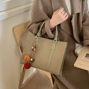 Stylish contrast color woven tote bag with leather handles and colorful pompom charm