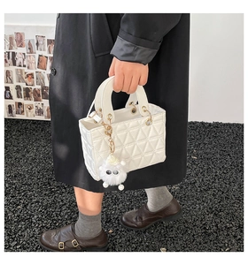 Détails du sac à main blanc matelassé avec fermoir doré et accessoire en peluche doux