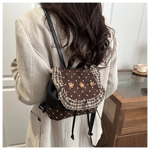 Rear view of a mini lace backpack with floral accents on a model in a home setting