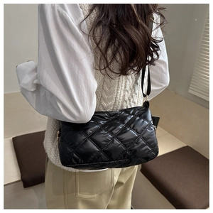 Détail d'un sac bandoulière en nylon noir matelassé avec finition brillante et zip doré