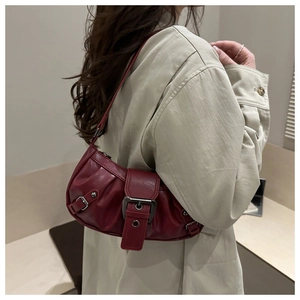 Detail view of deep red pleated shoulder bag with metallic buckle on an elegant leather strap