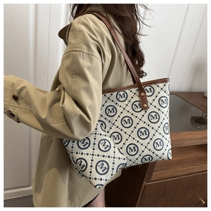 Detail view of large cream tote bag with brown leather trim and matching inner pouch