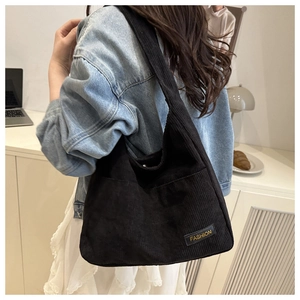 Detailed texture of black corduroy shoulder bag shown in a lifestyle home setting