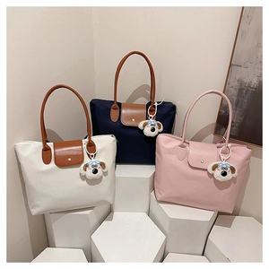 Three large nylon tote bags in white, navy, and pink with brown leather handles and dog charms
