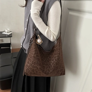Brown leopard print large tote bag with baseball charm shown on shoulder by model