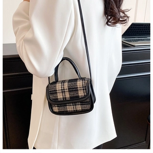 Fashionable plaid handbag with black leather trim shown worn as a crossbody bag