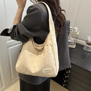 Minimalist beige corduroy hobo shoulder bag with fashion label shown on model